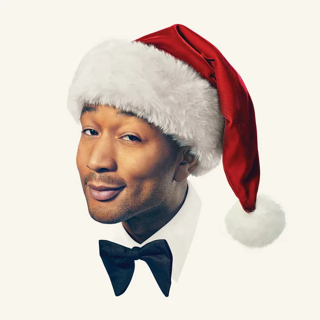 A Legendary Christmas cover: John Legend in a Santa hat and black bow tie, smiling, on cream